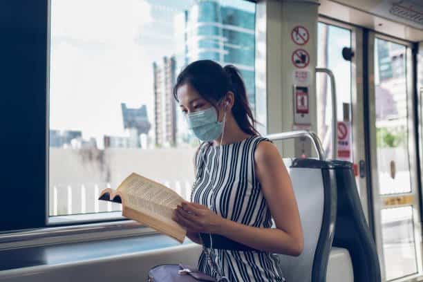 asian woman reading book in subway train